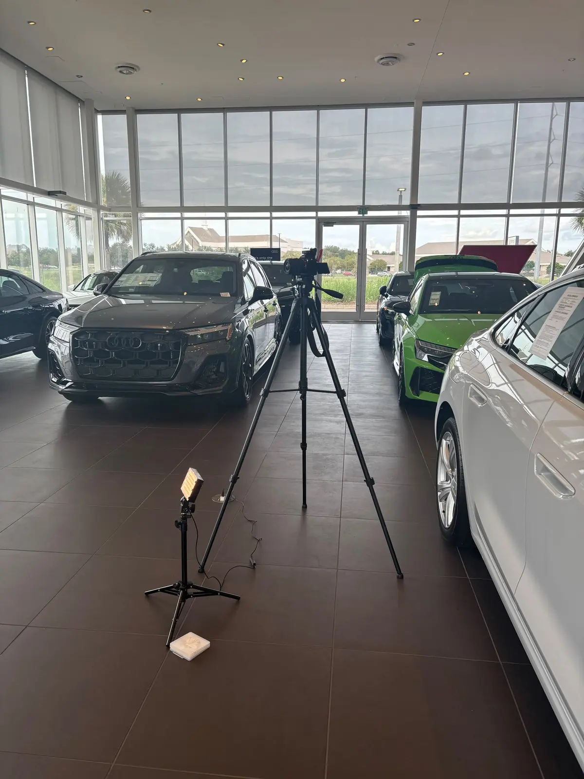 White electric sports sedan on a dealership showroom floor beside other vehicles