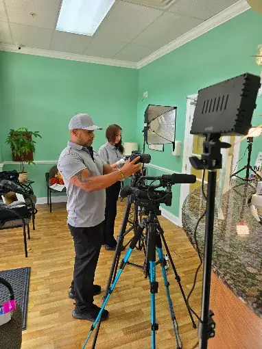 Insight Pros videographer operating a camera on a tripod inside a business